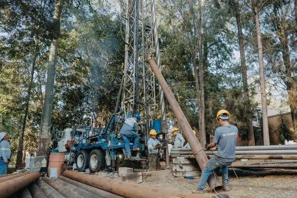 Equipo de perforación trabajando en un terreno arbolado