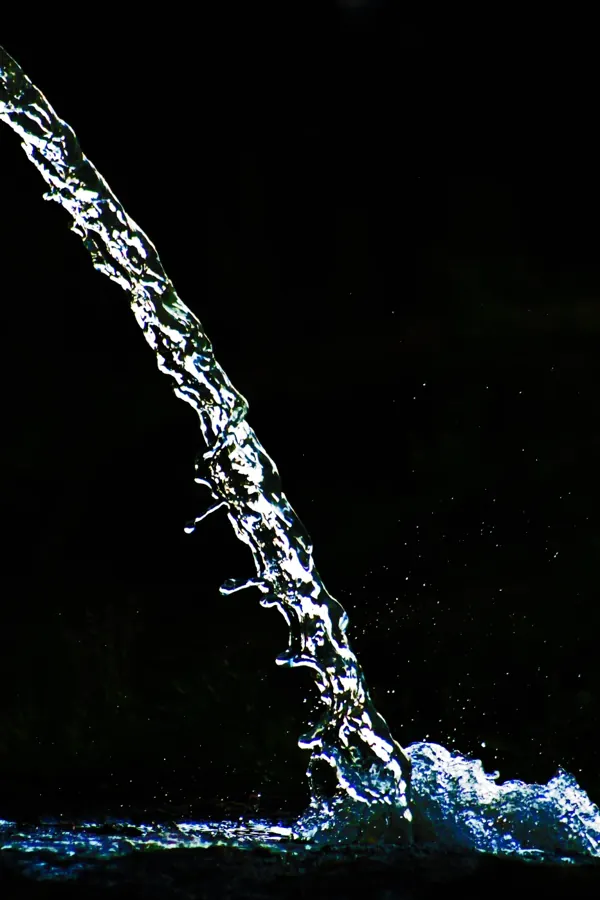 Un chorro de agua iluminado sobre un fondo oscuro